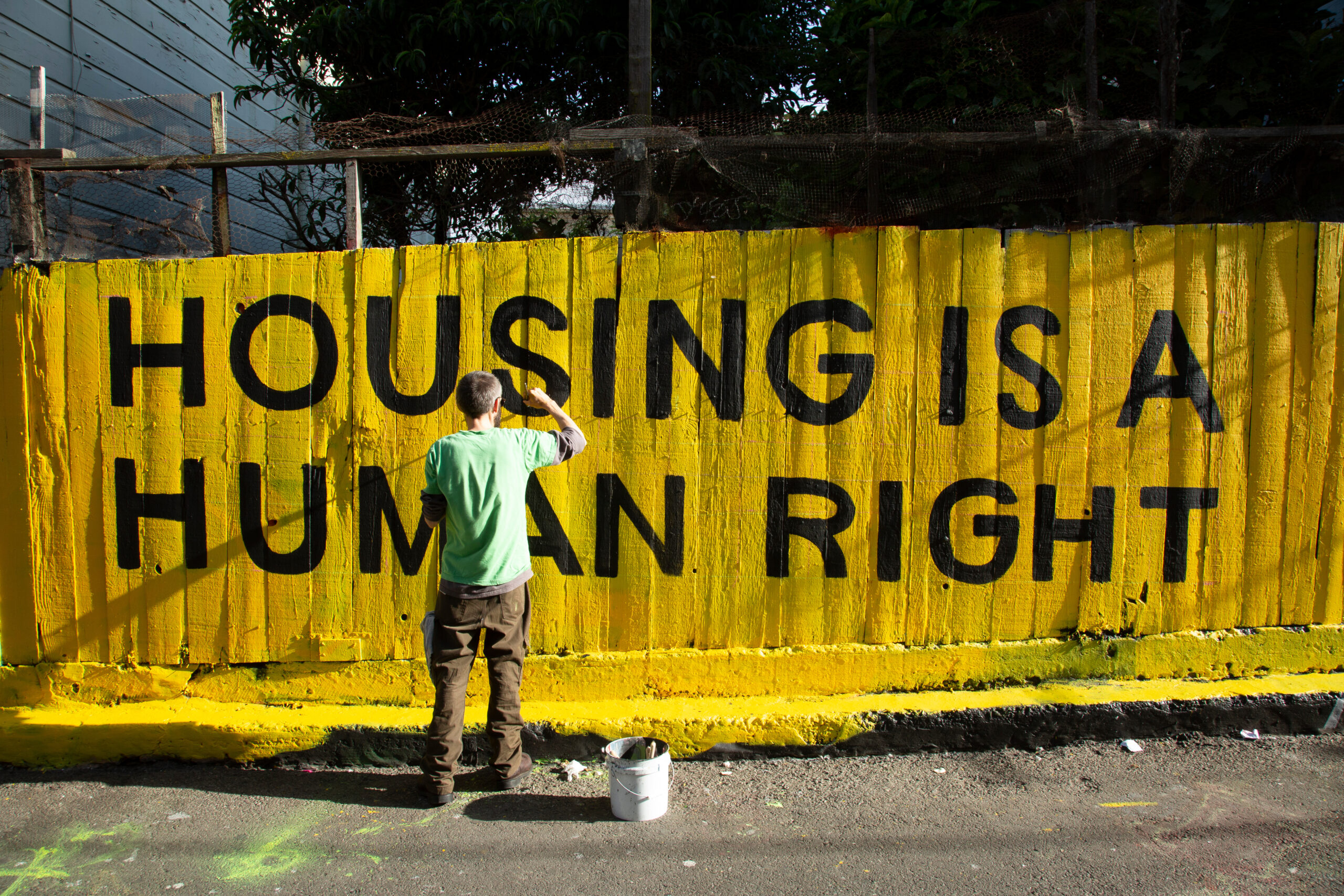 Housing is a human right sign being painted on fence